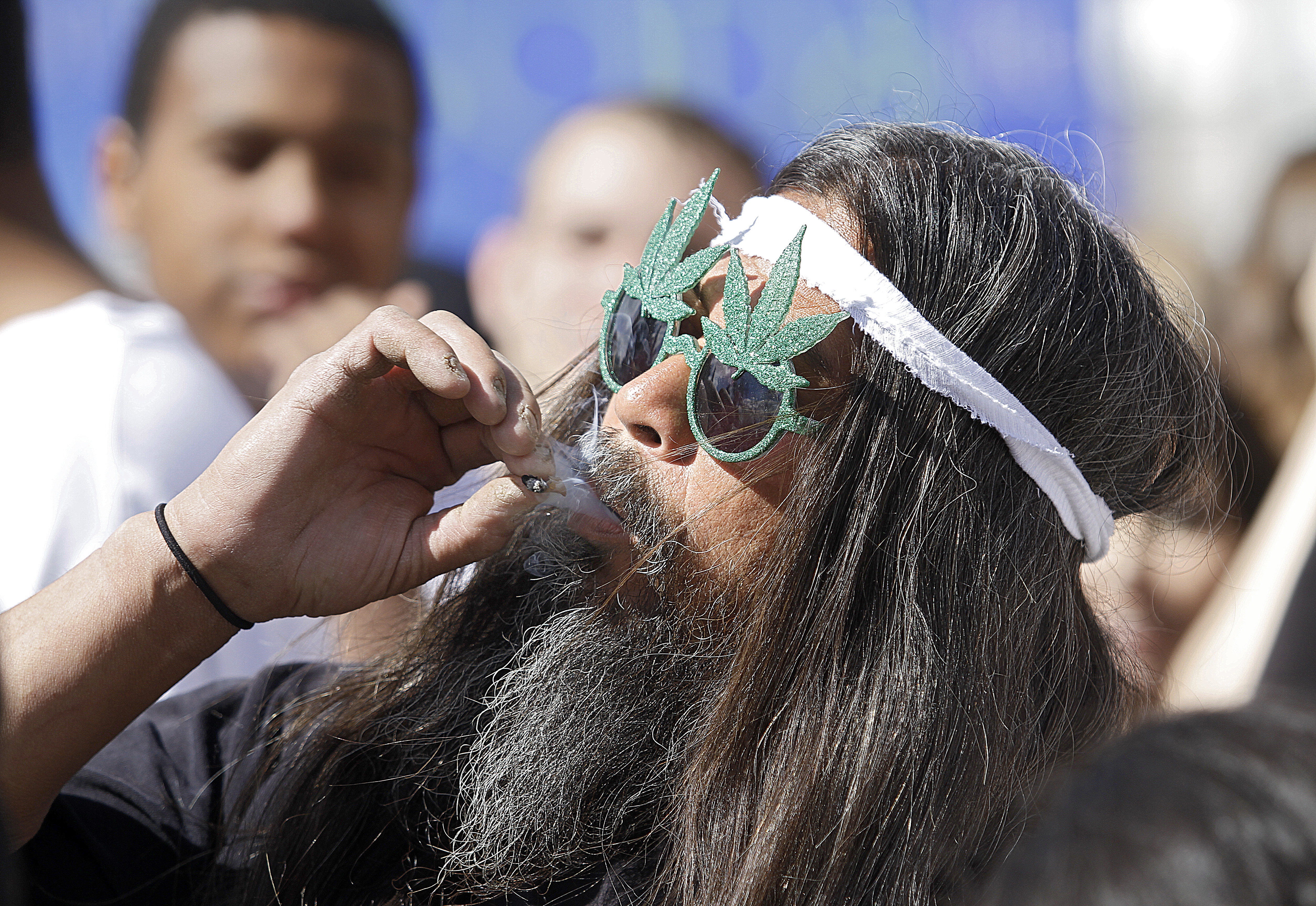 Fast Eddy Aki'a de Hawaii fuma un porro mientras miles de personas se reunieron para celebrar las leyes de marihuana medicinal del estado y encender colectivamente a las 4:20 p.m. en Civic Center Park el 20 de abril de 2012 en Denver, Colorado.