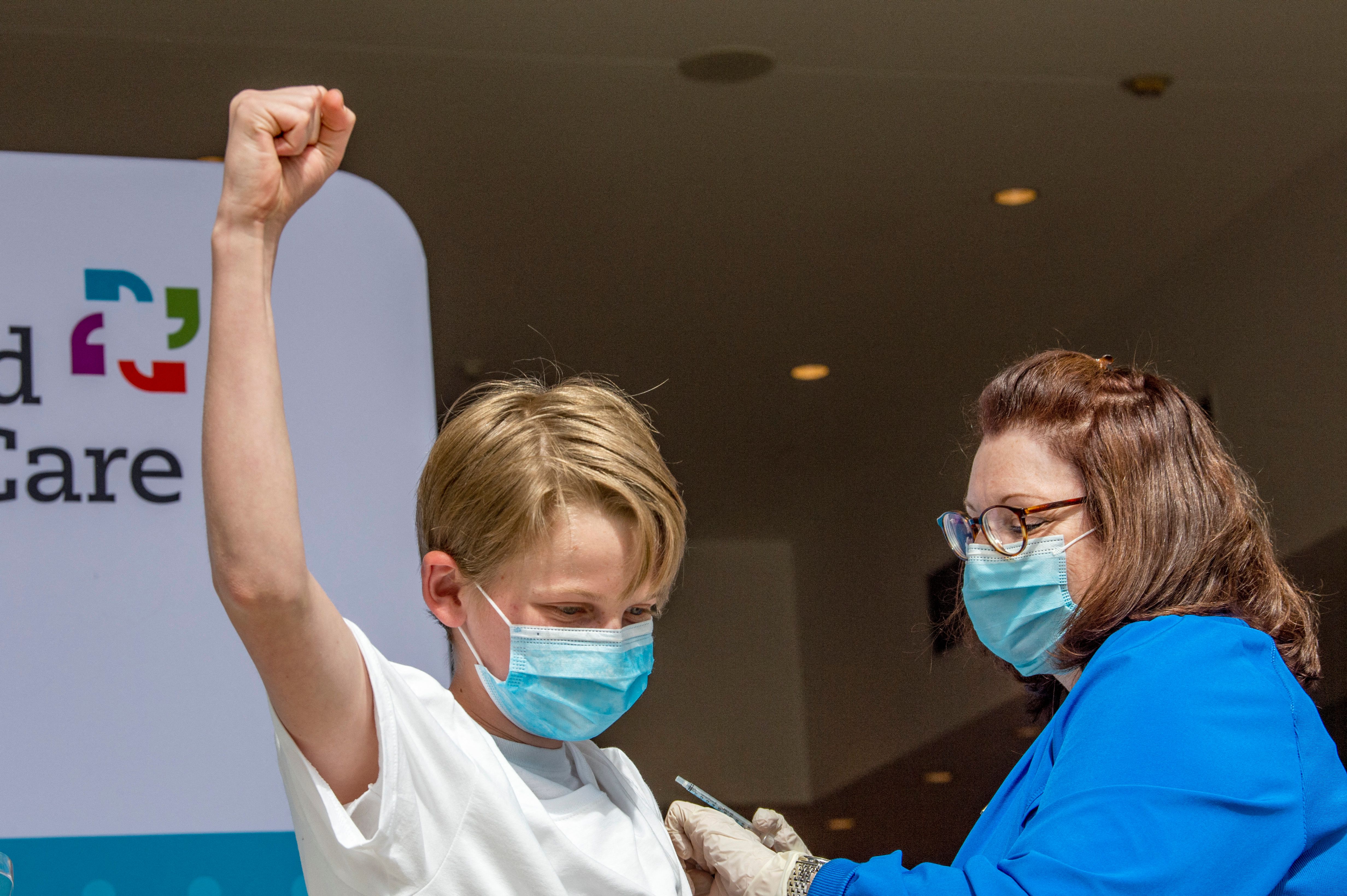 Charles Muro, de 13 años, celebra ser inoculado por la enfermera Karen Pagliaro en el centro de vacunación masiva Hartford Healthcares en el Centro de Convenciones de Connecticut en Hartford, Connecticut el 13 de mayo de 2021.