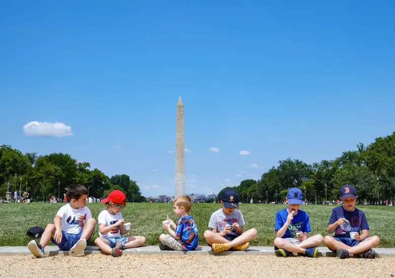 Un grupo de niños se sienta a disfrutar de un helado del camión de helados "America is Back" en el National Mall el 4 de julio de 2021 en Washington, DC.